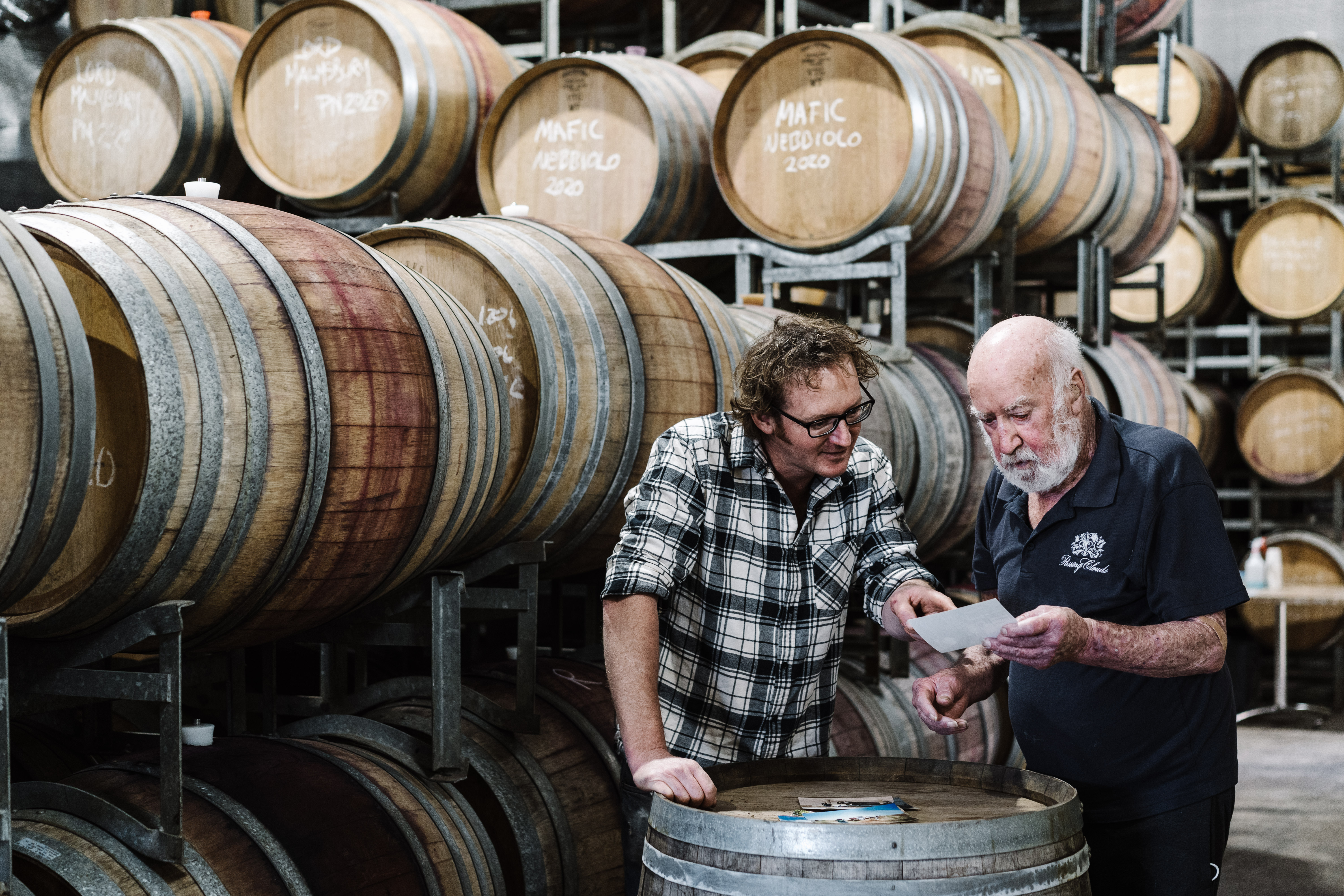 Two mean surrounded by wine barrels 